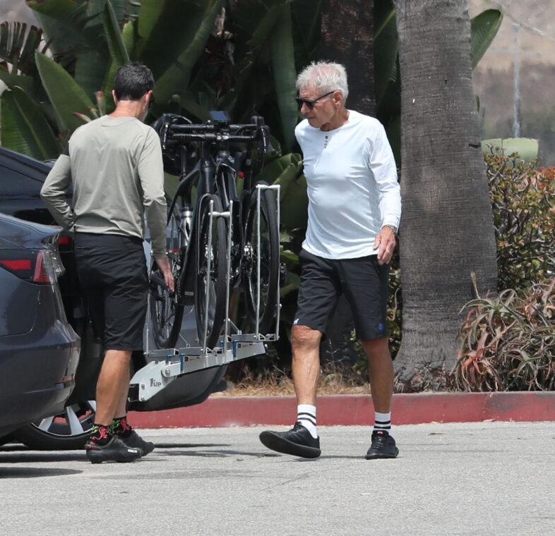 Harrison Ford walking beside a car with bikes mounted on the back.